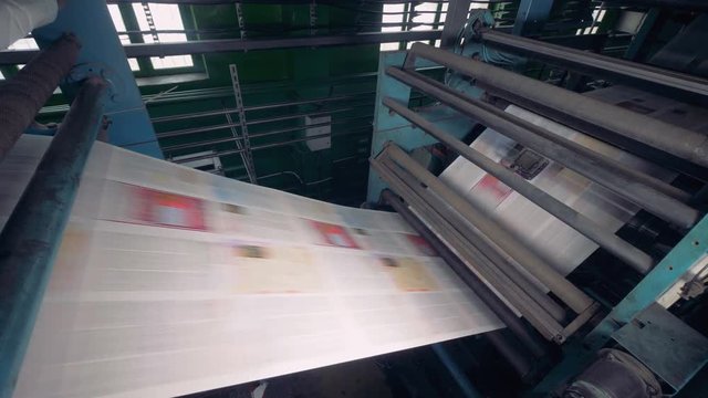 Modern equipment at a printing factory printing newspaper. 4K.