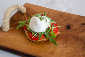Italian style toast with light bread, arugula, tomato and mozzarella cheese 