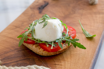 Italian style toast with light bread, arugula, tomato and mozzarella cheese 
