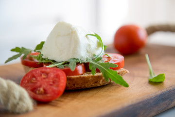 Fototapeta na wymiar Italian style toast with light bread, arugula, tomato and mozzarella cheese 