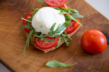 Italian style toast with light bread, arugula, tomato and mozzarella cheese 