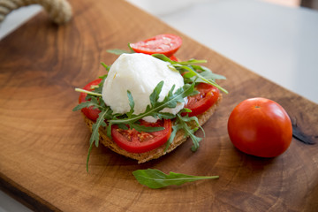 Italian style toast with light bread, arugula, tomato and mozzarella cheese 