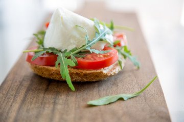 Italian style toast with light bread, arugula, tomato and mozzarella cheese 