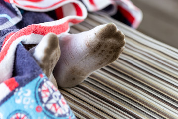 Pair of child feet in dirty stained white socks. Kid soiled socks while playing outdoors. Children clothes bleaching and washing troubles concept