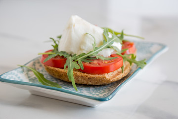 Italian style toast with light bread, arugula, tomato and mozzarella cheese 