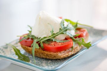 Italian style toast with light bread, arugula, tomato and mozzarella cheese 