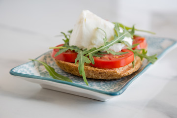 Italian style toast with light bread, arugula, tomato and mozzarella cheese 