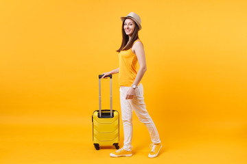 Traveler tourist woman in summer casual clothes, hat with suitcase isolated on yellow orange...