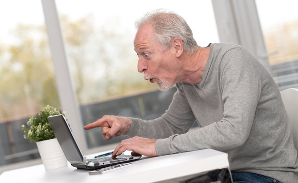 Happy mature man having a good surprise on laptop