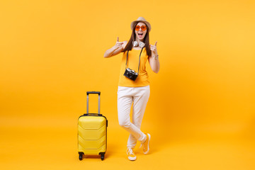 Fototapeta na wymiar Traveler tourist woman in summer casual clothes, hat with headphones on neck isolated on yellow orange background. Passenger traveling abroad to travel on weekends getaway. Air flight journey concept.