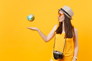 Traveler tourist woman in summer casual clothes, hat toss up globe isolated on yellow orange background. Female passenger traveling abroad to travel on weekends getaway. Air flight journey concept.