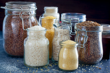 Various cereals in glass jars on a table, horizontal