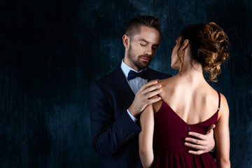 Elegant couple in love. Rich tidy neat man male hugs luxury woman female in red evening dress with expensive gold earrings. Romantic dating body part, sex social issues, relationship concept