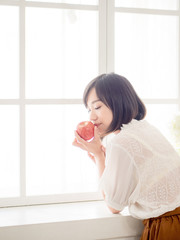 Woman eating fruit on window