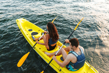 Rear view of a young couple kayaking on lake