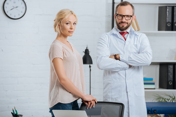 Obraz premium portrait of doctor in white coat and female patient looking at camera in clinic