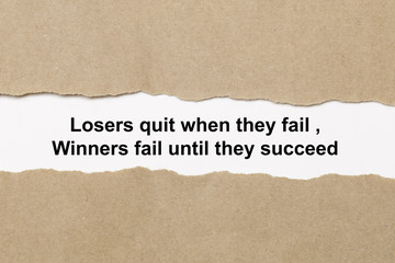 Fototapeta na wymiar Motivational quote Losers Quit When They Fail Winners Fail Until They Succeed appearing behind paper.