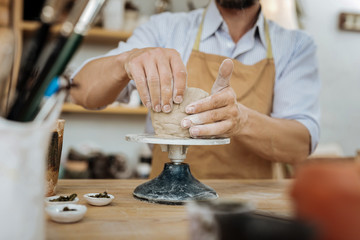 Experienced potter. Experienced professional potter wearing dark brown apron sitting near pottery wheel