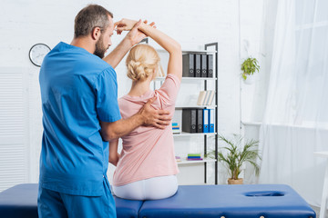 Fototapeta premium physiotherapist stretching patients arm on massage table in hospital