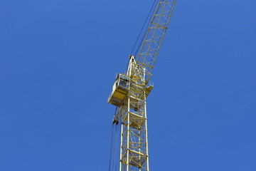 Fototapeta na wymiar Yellow tower crane, blue sky background.