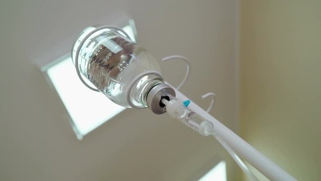 IV drip stand with saline solution above the hospital bed in a patient room
