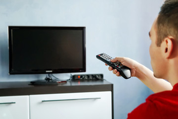 Turning the TV on or off. Men with the remote control, front of the television. Young guy switches...