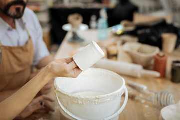 Bearded man. Bearded man wearing brown apron watching female ceramist making clay pots