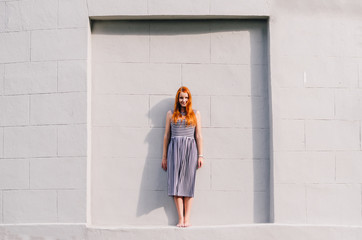 Young redhead woman over a grey background