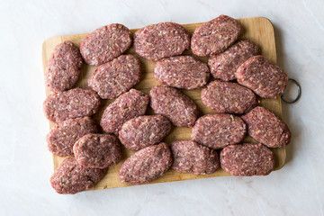 Turkish Raw Meatballs Kofte or Kofta made with Minced Meat on Wooden Surface.