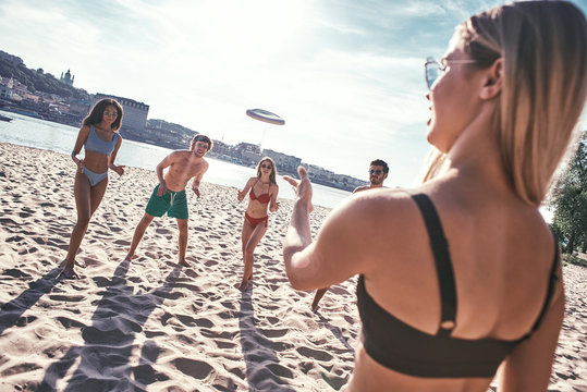 Time with friends. Group of young people playing freesby on the beach