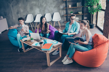 High angle view of four smart, clever, people in casual jeans, friends, beautiful attractive girls and handsome nerd guys researching information, discussing, preparing for test, meeting, gathering