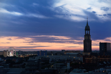Fototapeta na wymiar Ferris Wheel of Hamburg's Dom and St. Michael's church at sunset