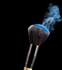 Make up brush with powder splashes on black background