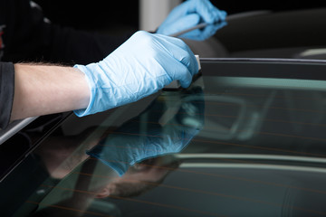 Worker applying ceramic coating on car windscreen