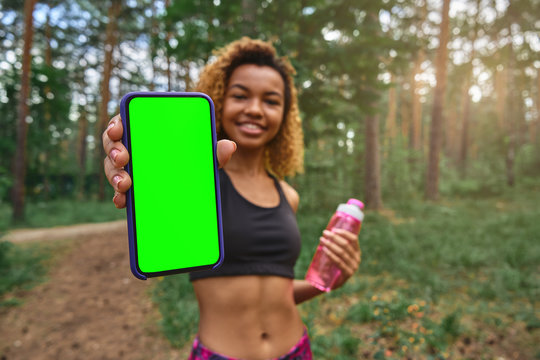 Black Young Woman Shows Smartphone Green Screen To The Camera After Jogging