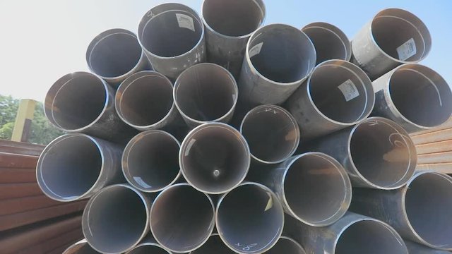 Metal pipes of large diameter in a metal warehouse, large pipes in an open-air warehouse, large diameter pipes stacked in rows