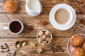 Breakfast and coffee for two persons, pastries, brown sugar and cinnamon with anise on a wooden background.