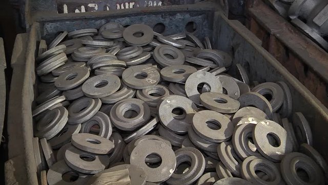 Cast cast-iron parts of round shape. O-ring made of cast iron. Many metal rings lie in the container.