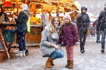 Little cute kid girl and young mother having fun on traditional German Christmas market during...