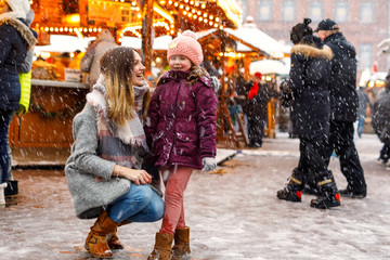 Little cute kid girl and young mother having fun on traditional German Christmas market during...