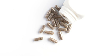 herb capsules spilling out of a bottle isolated