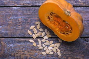 Fresh ripe pumpkin - the half of vegetable with seeds on a wooden background