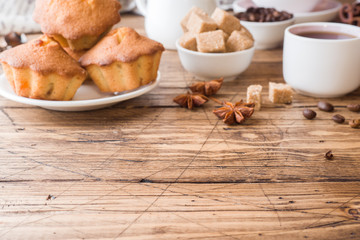 Breakfast coffee with milk, pastries, brown sugar and cinnamon with anise on wooden background. Copy space