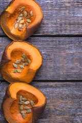 Vegetarian organic set from yellow pumpkin and seeds on a wooden background.