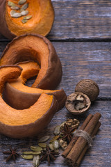 Baked pumpkin with species cinnamon, walnuts, pumpkin seeds on a wooden background.