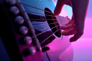 Closeup of an acoustic guitar played by a girl - obrazy, fototapety, plakaty