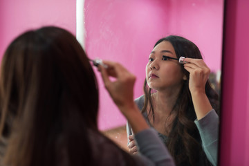 girl applying mascara to eyelashes