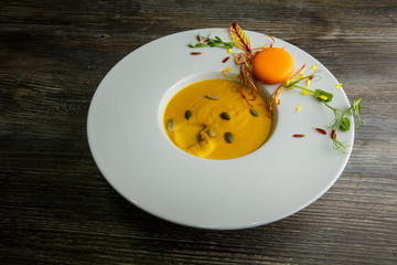 fresh pumpkin cream soup with orange macaroon decoration