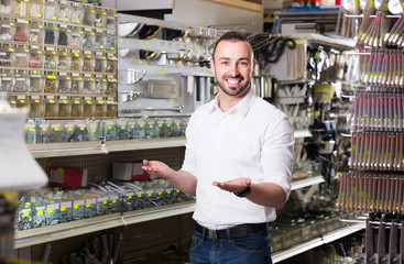  man standing next to showcase with various plastic rawlplugs and  choosing one