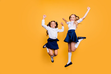 Dynamic images. Motion, movement, action concept. Full length, legs, body, size portrait of carefree, careless, adorable, beautiful, small girls jumping isolated on yellow background